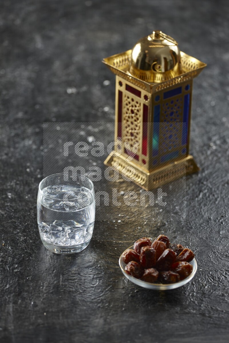 A golden lantern with different drinks, dates, nuts, prayer beads and quran on textured black background