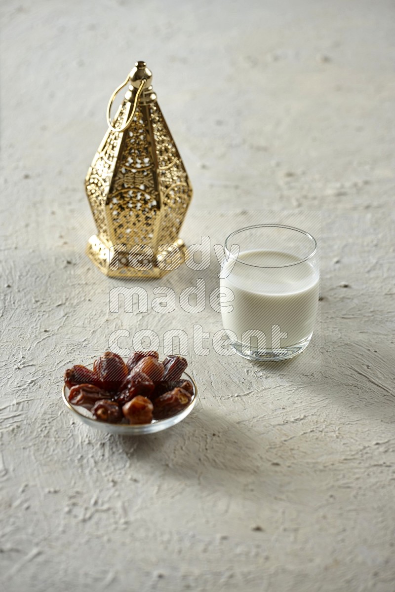 A golden lantern with different drinks, dates, nuts, prayer beads and quran on textured white background