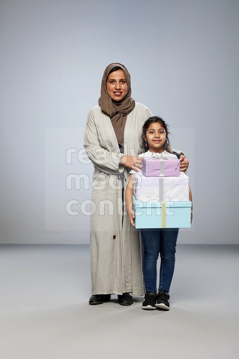 A girl giving a gift to her mother on gray background