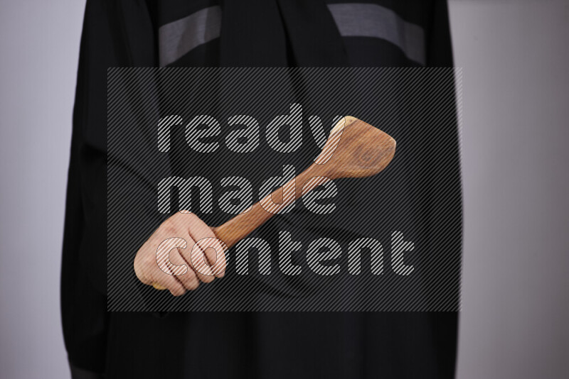A woman in black abaya holding different wooden essentials in different positions