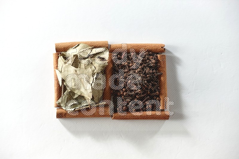 2 squares of cinnamon sticks full of cloves and bay laurel leaves on white flooring
