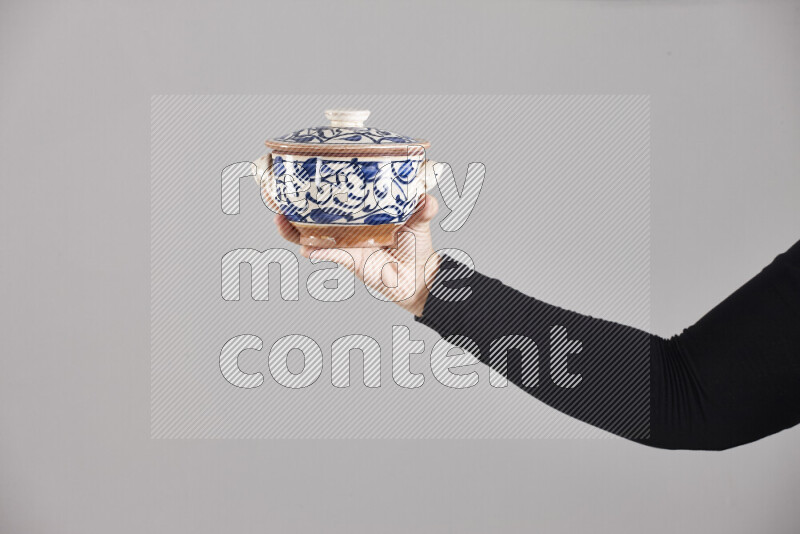 A woman in black abaya holding different pottery essentials in different positions