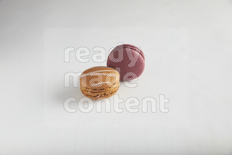 45º Shot of of two assorted Brown Irish Cream, and Red Cherry macarons on white background