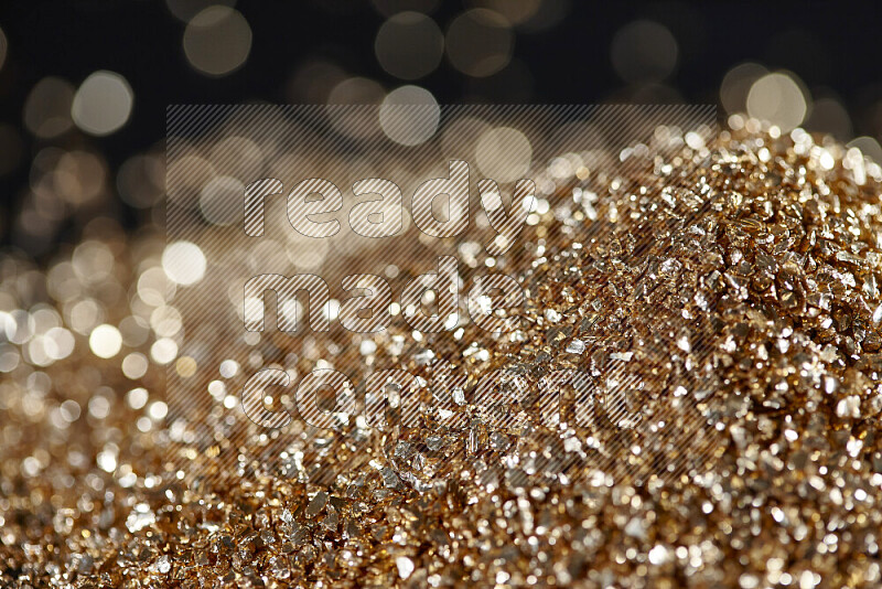 Gold shimmering fragments of glass scattered on a black background