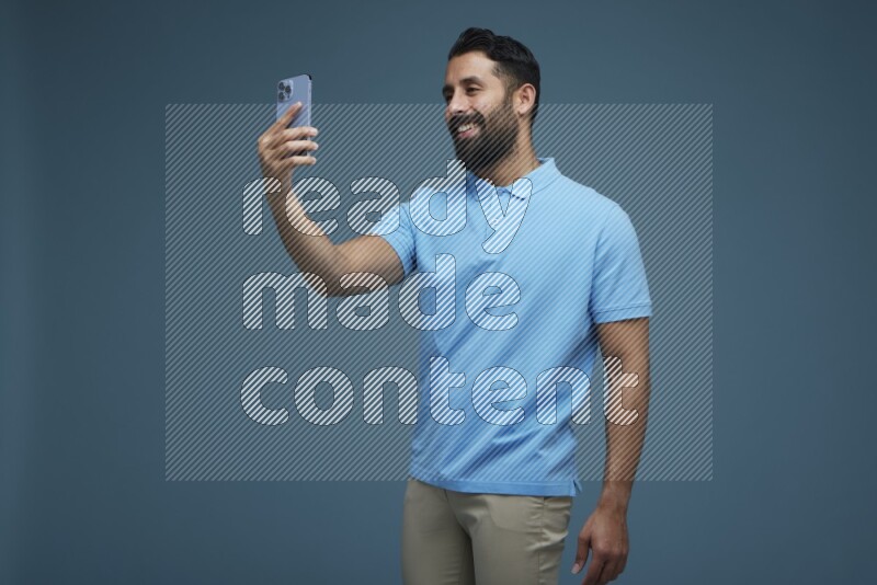 Man Taking a Selfie in a blue background wearing a Blue shirt