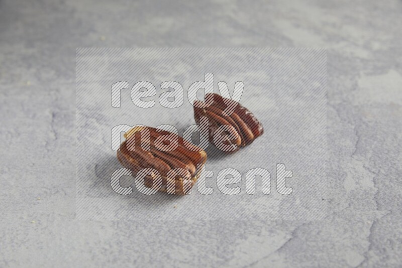 TWO pecan stuffed dates on alight grey background