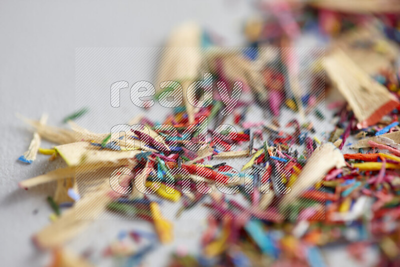 This image showcases a vibrant multicolored pencil shavings scattered on grey background