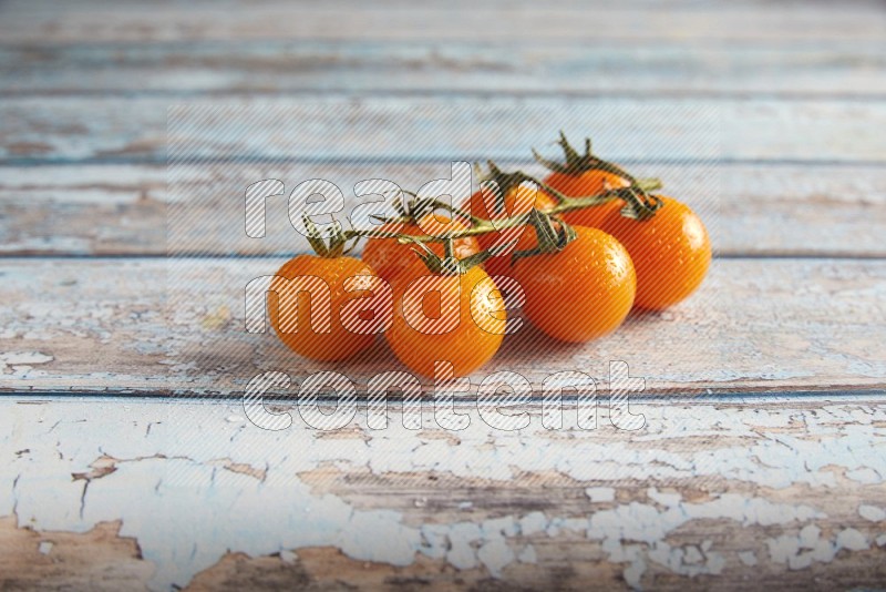 orange cherry tomato vein on a textured blue wooden background 45 degree