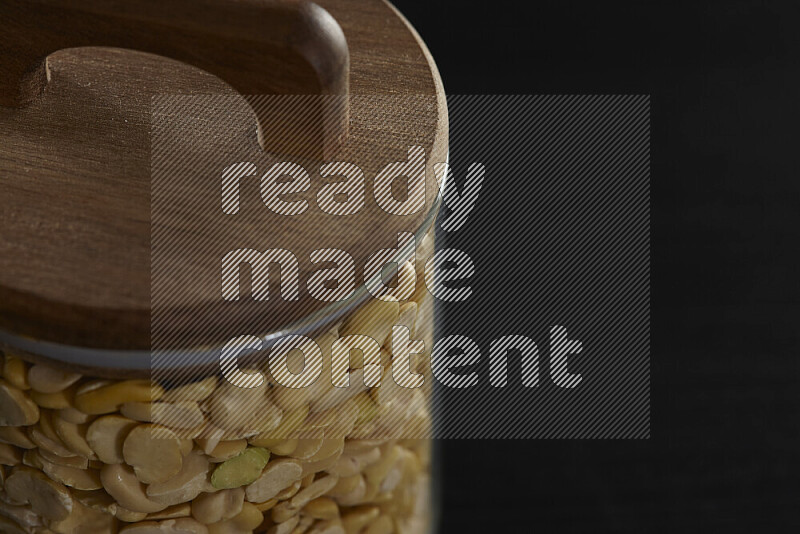 Crushed beans in a glass jar on black background