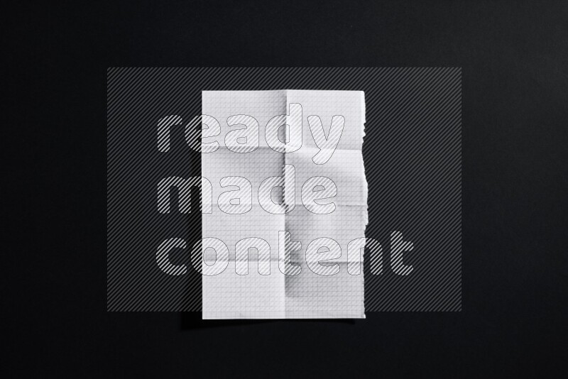 Folded notebook sheet on black background