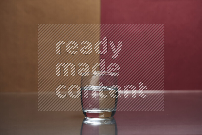 The image features a clear glassware filled with water, set against brown and dark red background