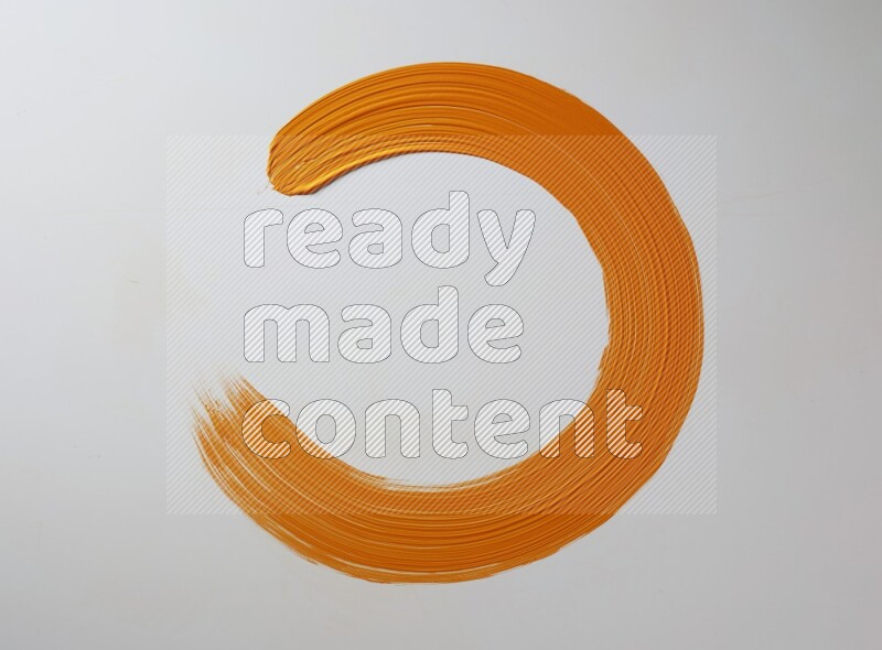 An orange circular painting brush stroke on white background