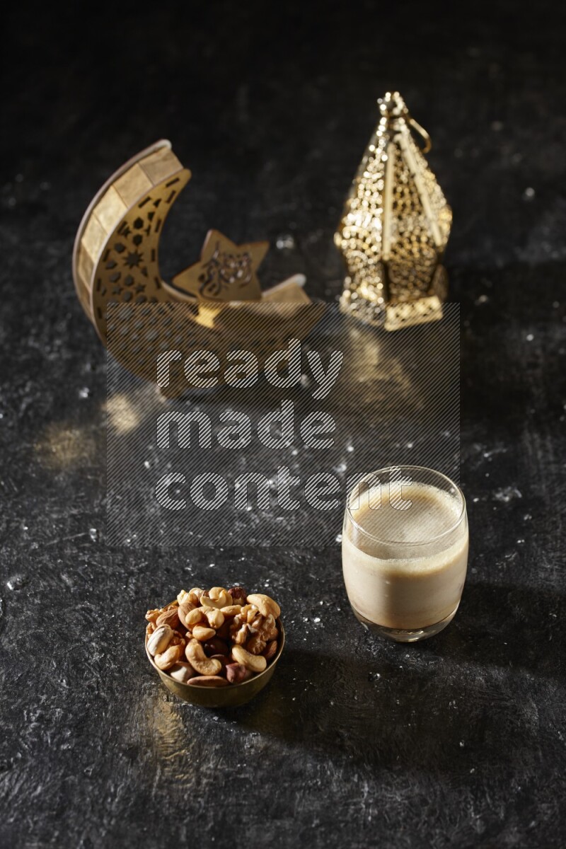 مكسرات في وعاء معدني مع مشروب التمر بجانب فوانيس ذهبية علي خلفية سوداء