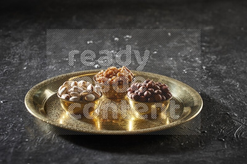 مكسرات في أطباق معدنية على صينية علي خلفية سوداء