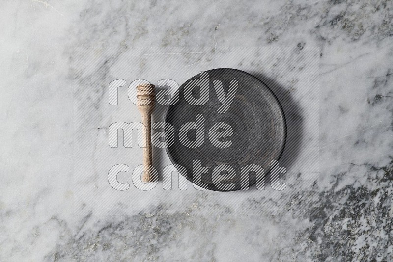 Black Pottery Plate with wooden honey handle on the side on grey marble flooring, Top view