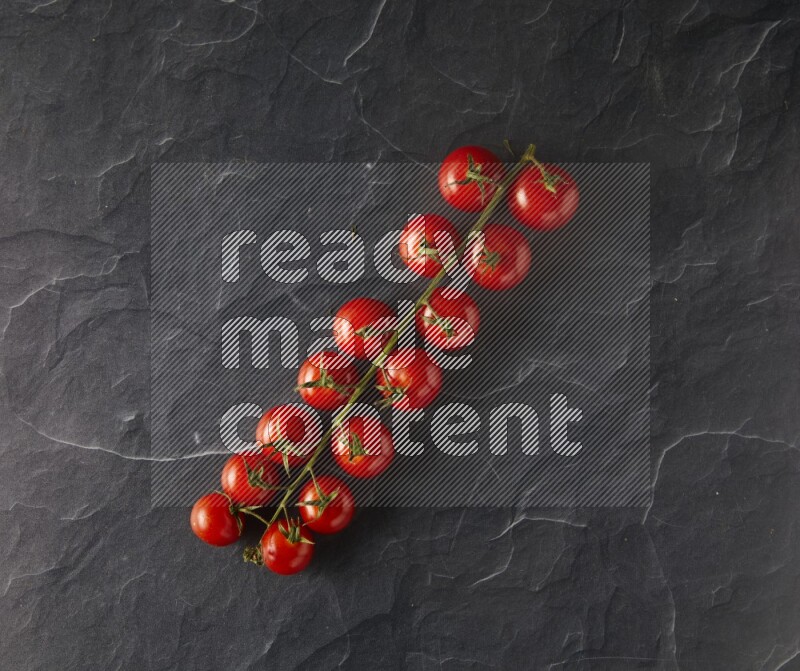 single cherry tomato vein topview on a black slate background