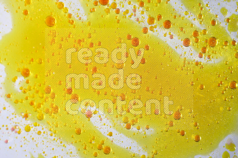 لقطات مقربة لقطرات ألوان مائية صفراء وحمراء على سطح الزيت على خلفية بيضاء