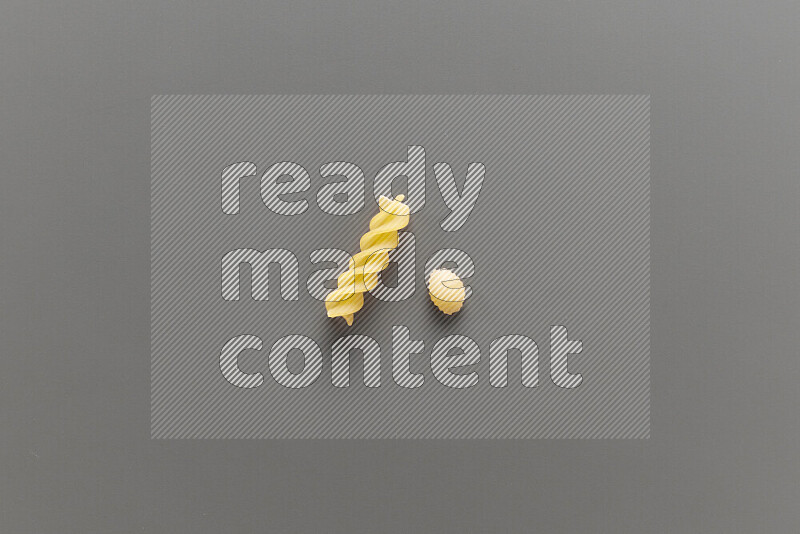 Shells pasta with other types of pasta on grey background