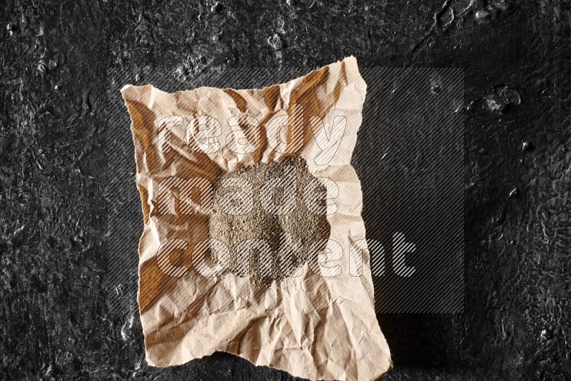 بودرة الفلفل الأسود في قطعة من الورق علي خلفية سوداء