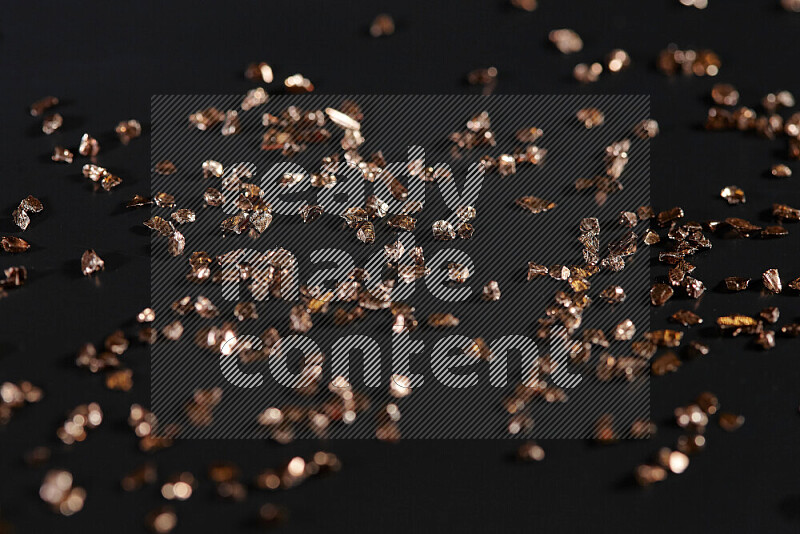 Bronze shimmering fragments of glass scattered on a black background