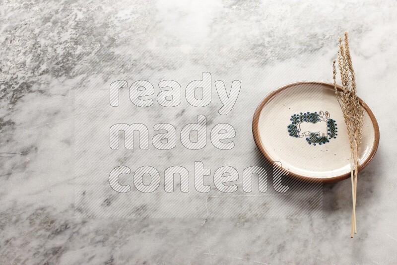 Wheat stalks on decorative pottery plate on grey marble background
