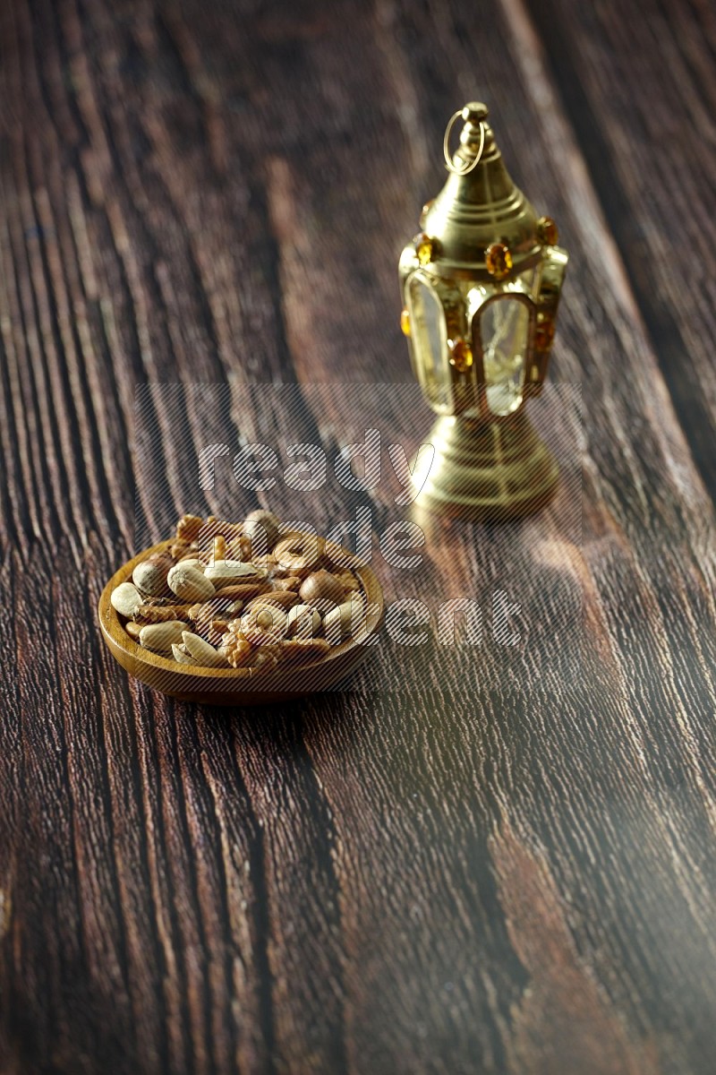 A golden lantern with different drinks, dates, nuts, prayer beads and quran on brown wooden background