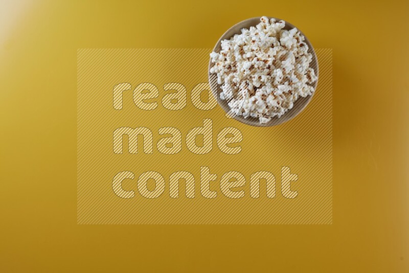 A multicolored ceramic plate full of popcorn on a yellow background in different angles