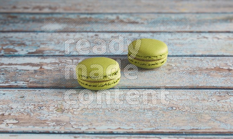 45º Shot of two Green Pistachio macarons on light blue wooden background