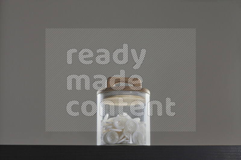 أزرار متنوعة في وعاء زجاجي علي خلفية سوداء