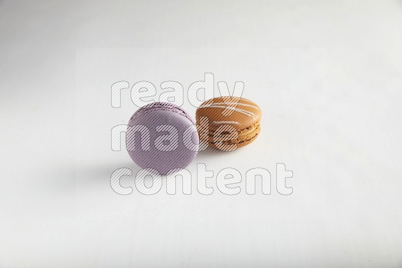 45º Shot of of two assorted Brown Irish Cream, and Purple Blueberry macarons on white background