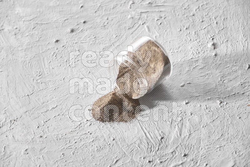 فلفل أسود مطحون في وعاء زجاجي مقلوب علي خلفية بيضاء