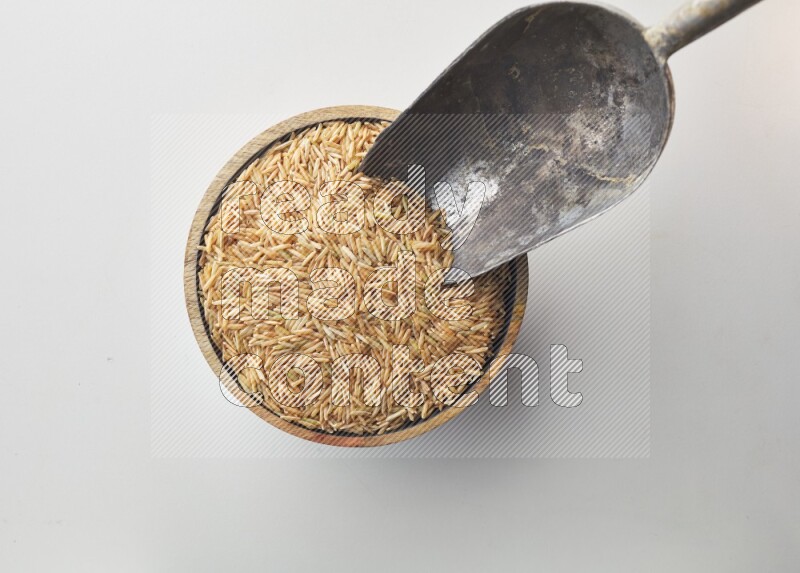 Top-view shot of long grain brown rice in a container on white background