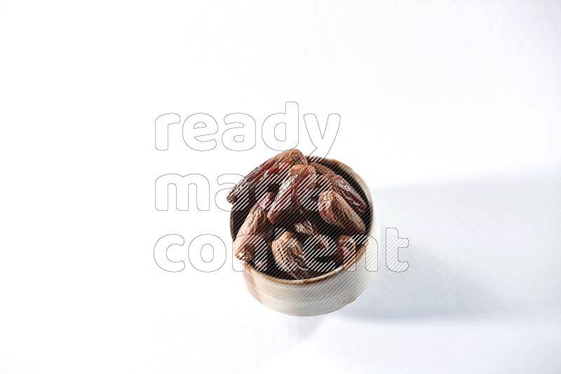 A beige ceramic bowl full of dried dates on a white background in different angles