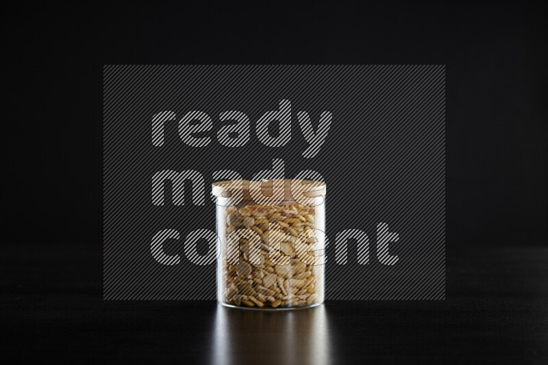 Crushed beans in a glass jar on black background