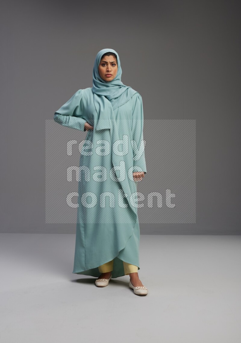 Saudi Woman wearing Abaya standing interacting with the camera on Gray background
