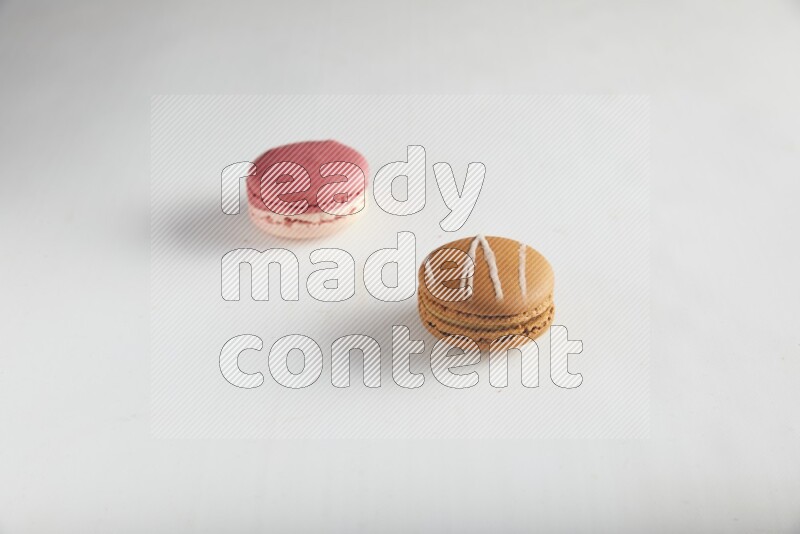 45º Shot of of two assorted Brown Irish Cream, and Pink Litchi Raspberry macarons on white background
