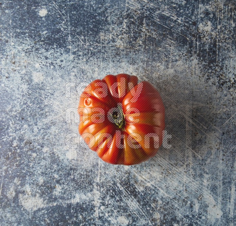 Single Topview Heirloom Tomato on a textured rustic blue background