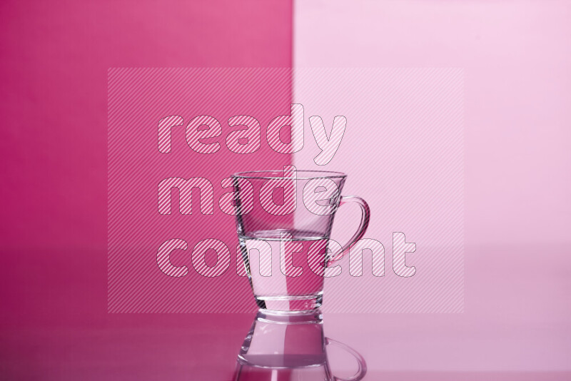 The image features a clear glassware filled with water, set against pink background