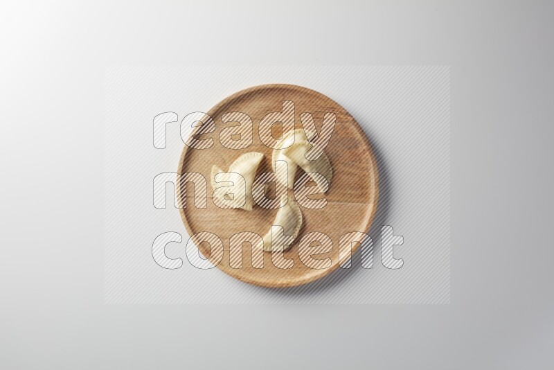 Five Sambosas on a wooden round plate on a white background