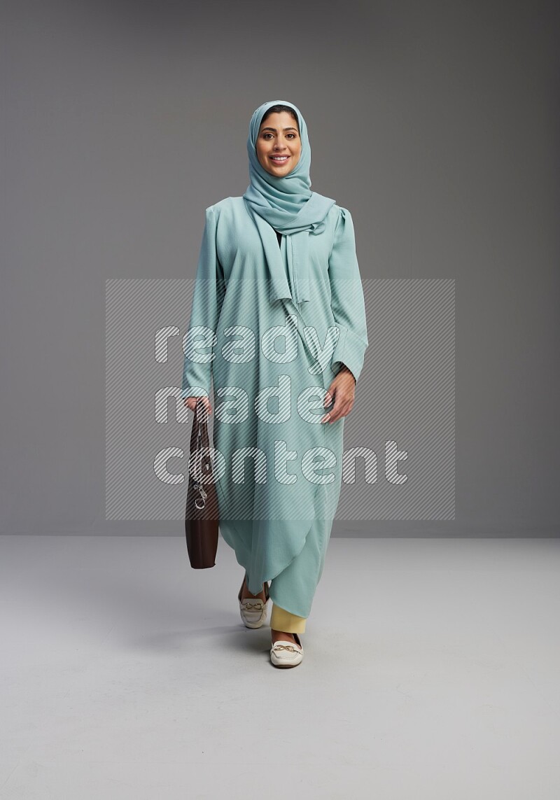 Saudi Woman wearing Abaya standing holding bag on Gray background