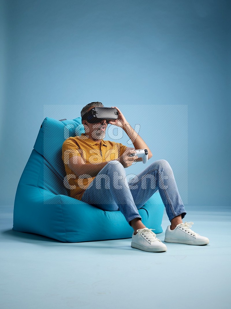 A man sitting on a blue beanbag and gaming with VR