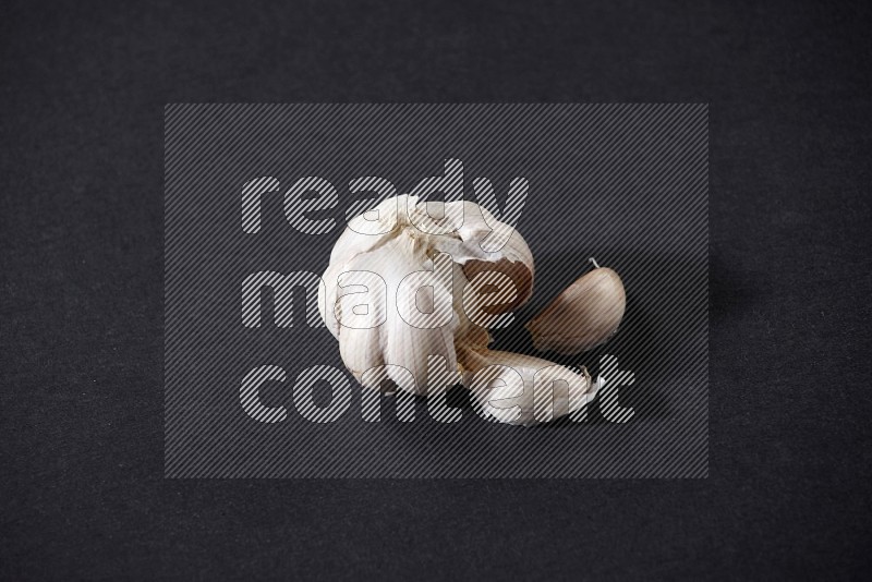 A whole garlic bulb on a black flooring in different angles