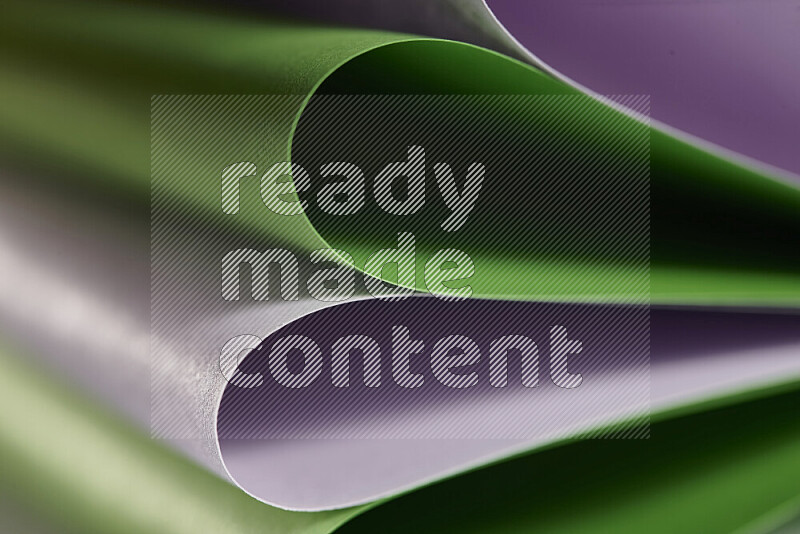 An abstract art showing purple and green paper sheets arranged in an overlapping curves