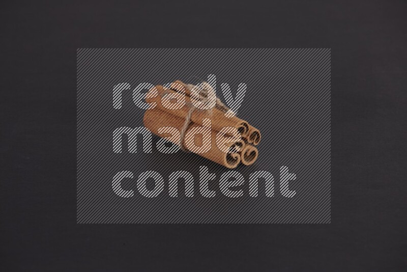 4 Cinnamon sticks stacked and bounded on black flooring