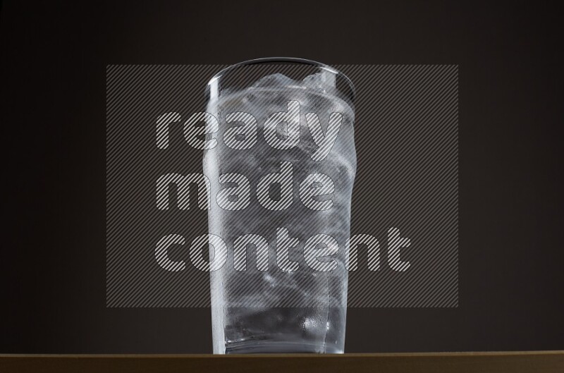 Low angle shot of a glass of water and ice on grey background