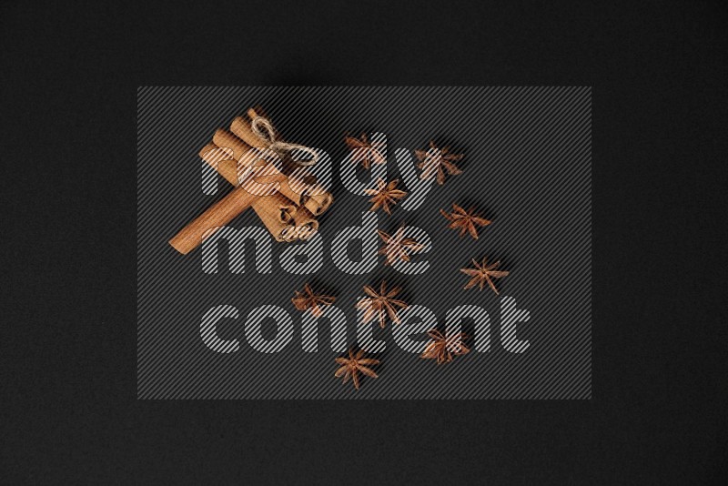 Cinnamon sticks stacked and bounded and star anise on black background