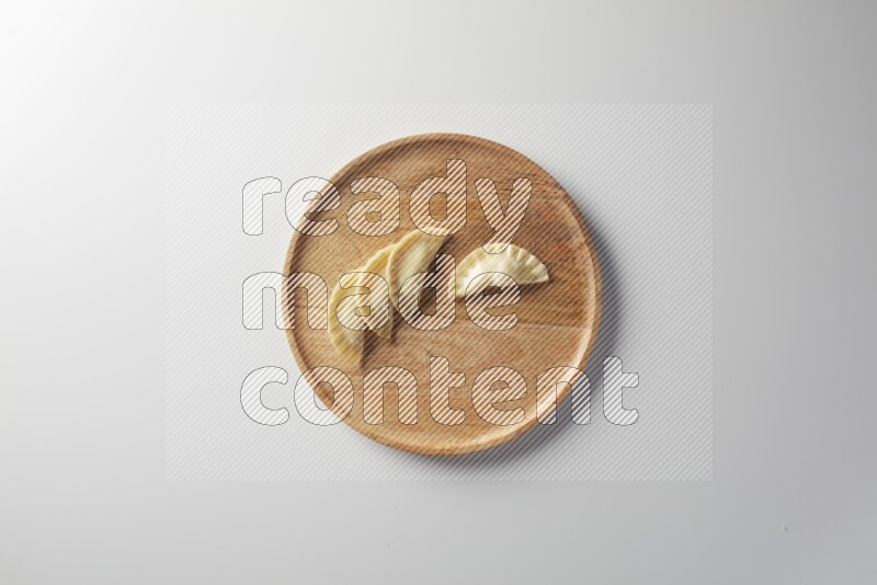 Four Sambosas on a wooden round plate on a white background
