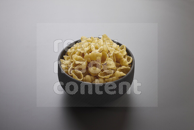 Snails pasta in a pottery bowl on grey background