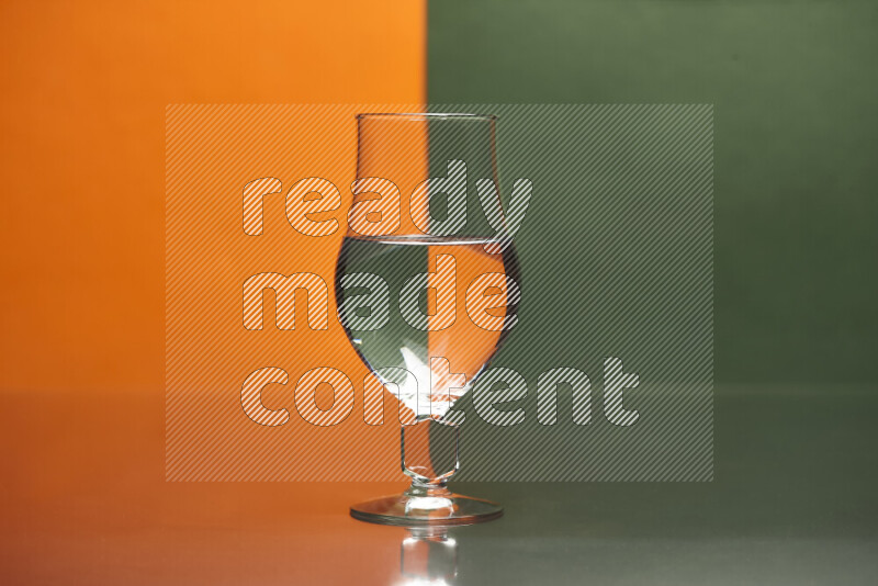 The image features a clear glassware filled with water, set against orange and dark green background