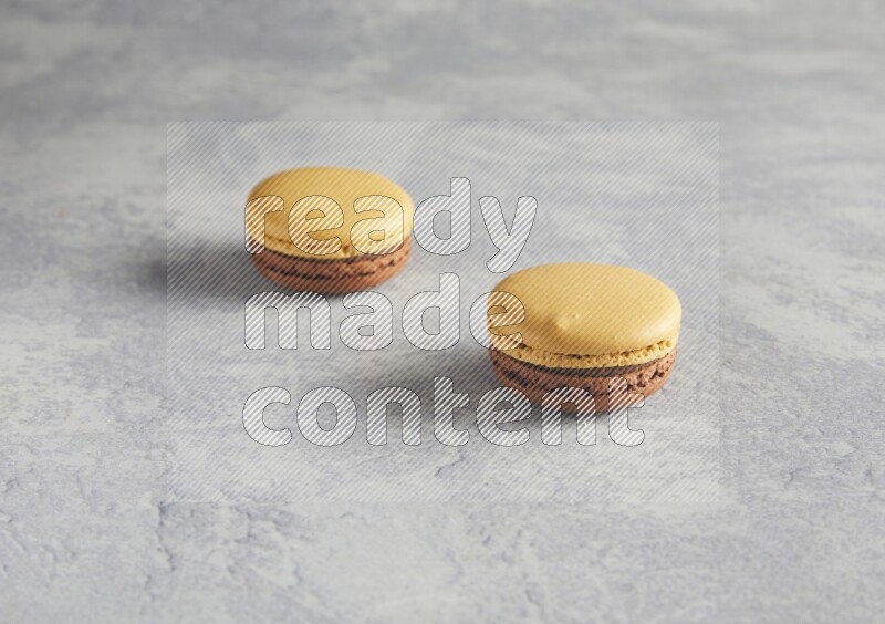 45º Shot of two Yellow and Brown Chai Latte macarons r on white  marble background